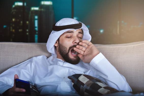Arab muž zívajúci pri sledovaní televízie.