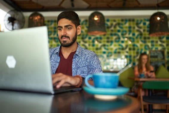 Indický muž pracujúci v trendovom coworkingovom priestore.