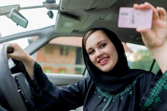 Moslimská žena šoféruje auto, drží vodičský preukaz.