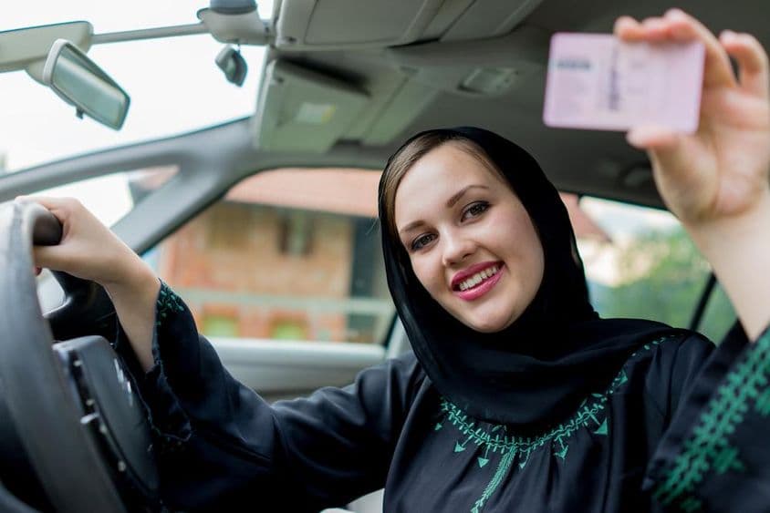 Moslimská žena šoféruje auto, drží vodičský preukaz.