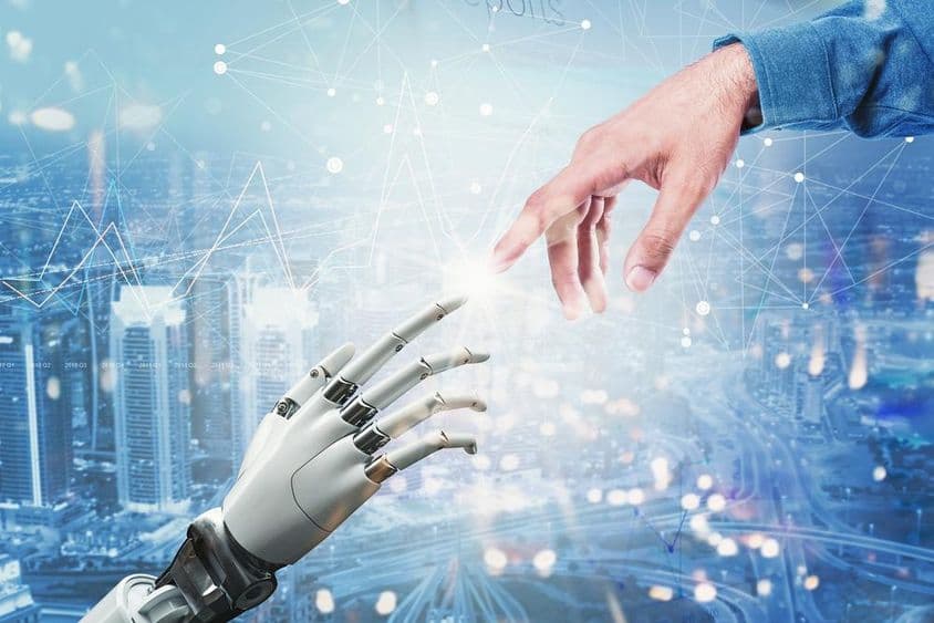 3D robotická ruka stretávajúca sa s ľudskou rukou nad futuristickým mestom.