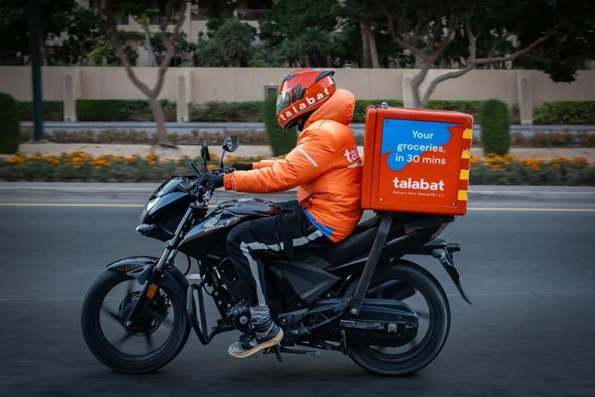 Motocyklista doručujúci jedlo, kuriér Talabat na ceste v Dubaji.