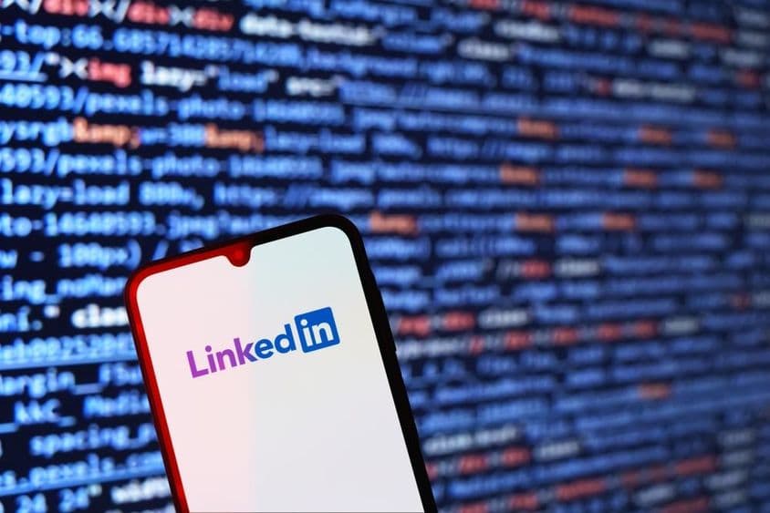 Smartfón zobrazujúci logo LinkedIn s kódom na pozadí.