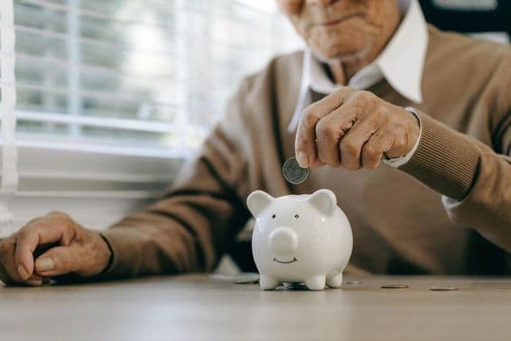 Sporenie peňazí, starší muž vkladajúci mince do prasiatka