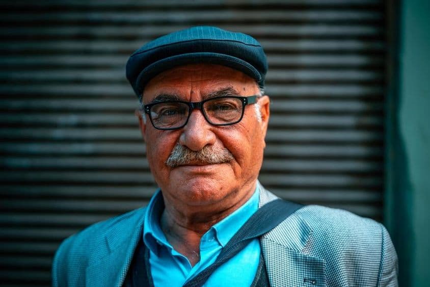 Starší muž s klobúkom na ulici.