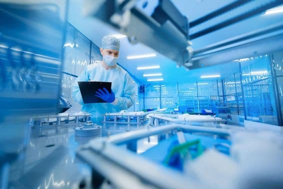Farmaceutický pracovník obsluhujúci výrobnú linku v farmaceutickom priemysle.