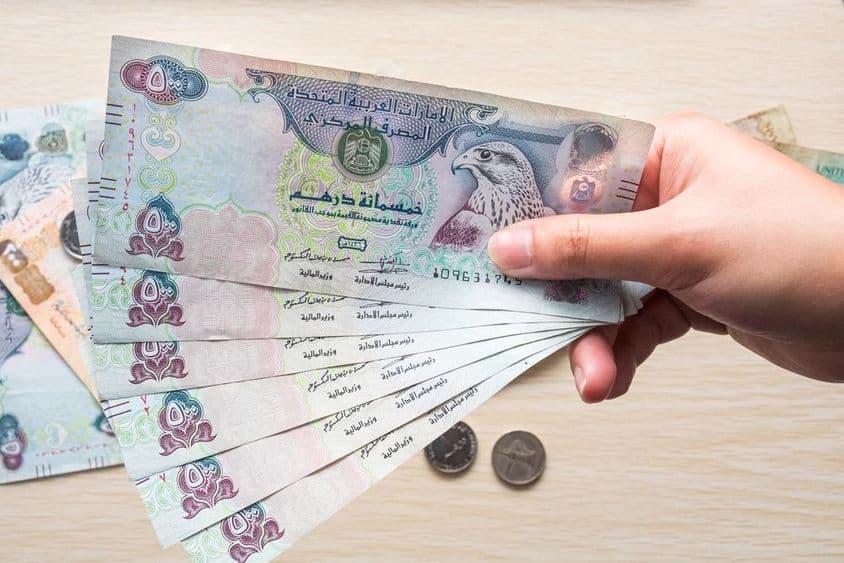 Dievča drží bankovky 500 UAE dirham, papierové peniaze.