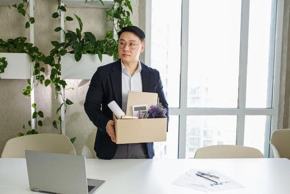 Muž, ktorý prichádza o prácu, balí si osobné veci do kartónovej krabice.