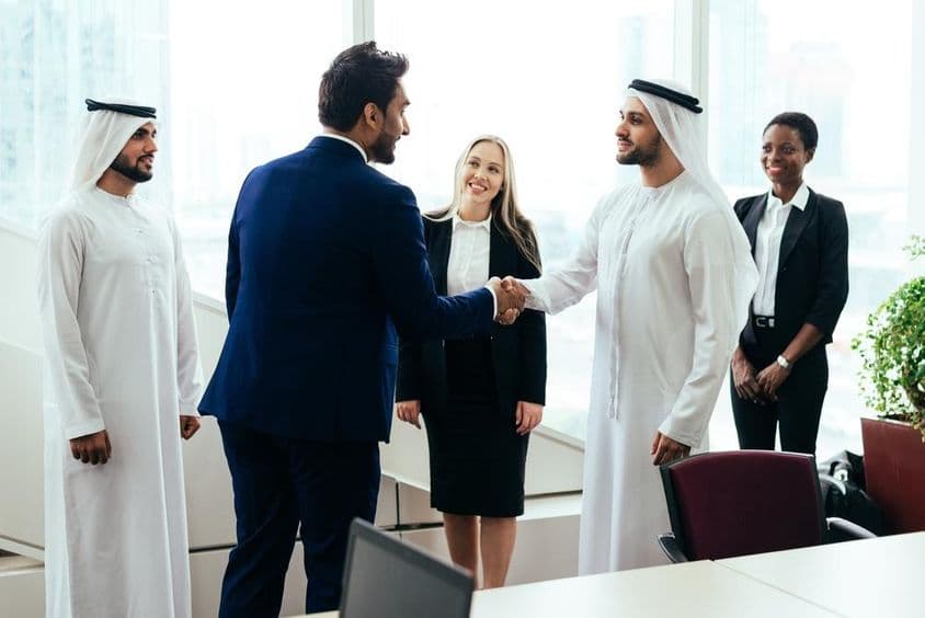 Multinárodný západný a stredovýchodný obchodný tím pracujúci spoločne v kancelárii v Dubaji.