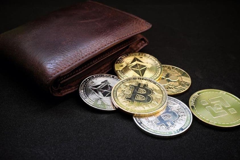 Peňaženka s rôznymi kryptomenami ako Bitcoin a Ethereum na čiernom pozadí.