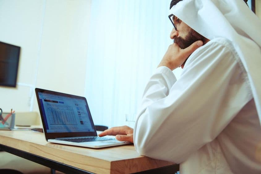 Arabský obchodník pracujúci online v pohodlnej kancelárii