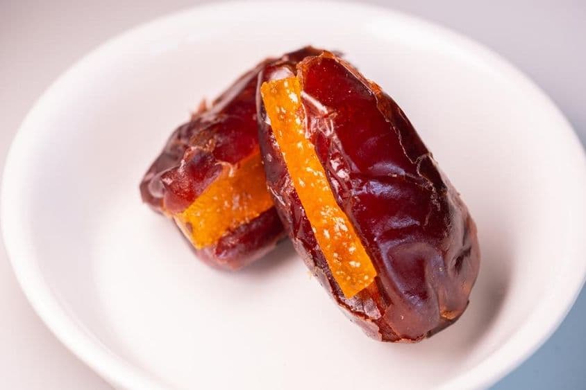 Dve úžasné veľké čerstvé dubajské datle s cukrovými pomarančovými kúskami.