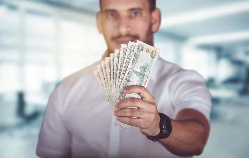 Muž držiaci hrst emirátskej hotovosti.