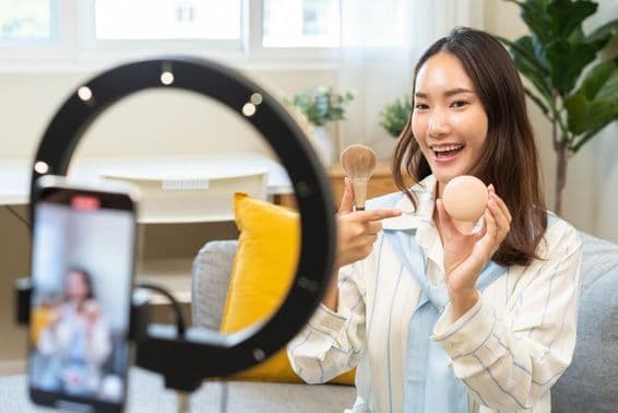 Mladá influencerka sa nahráva na smartphone pri tvorbe podcast videa.