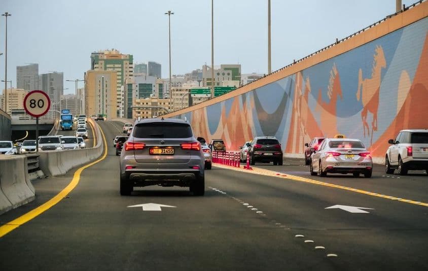 Auto premávka na diaľnici so mrakodrapmi v pozadí v Dubaji, Spojené arabské emiráty.