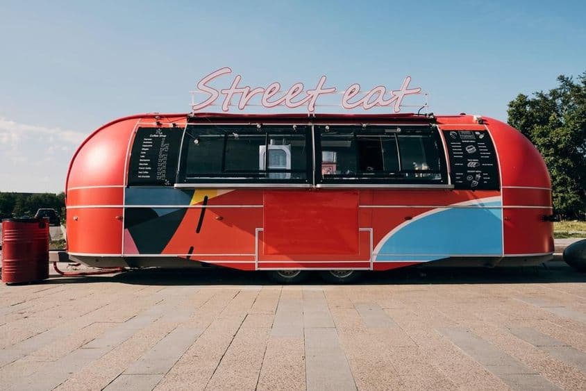 Červený food truck, predaj rýchleho občerstvenia uprostred ulice alebo námestia.