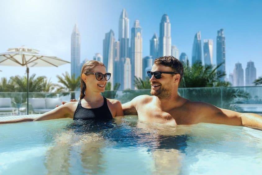 Šťastný mladý pár relaxuje v exteriérovom jacuzzi v Dubaji.