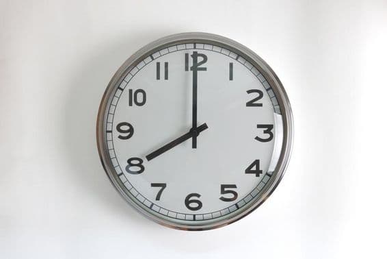 Okrúhle, nerezové nástenné hodiny s bielym ciferníkom.