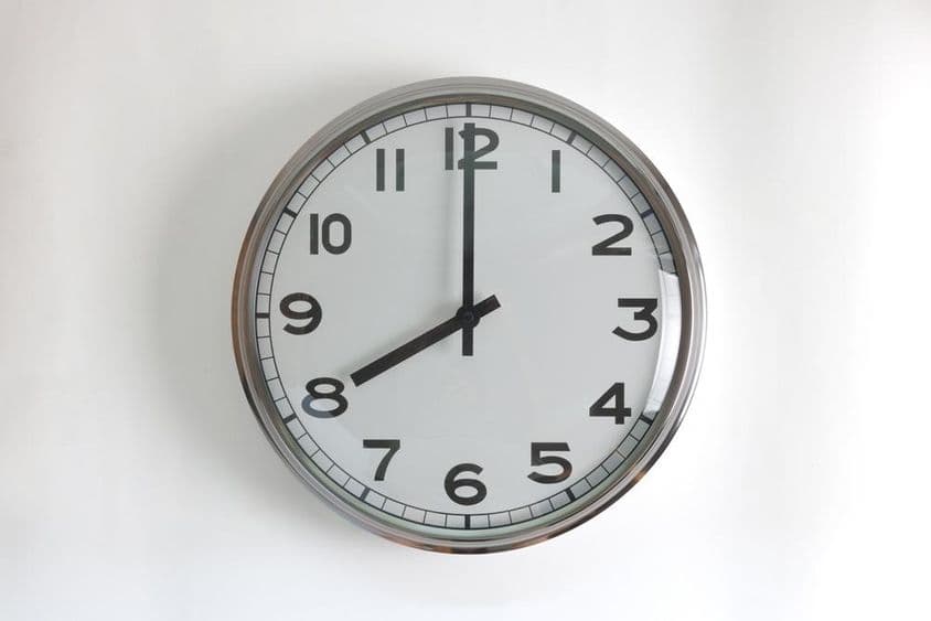 Okrúhle, nerezové nástenné hodiny s bielym ciferníkom.