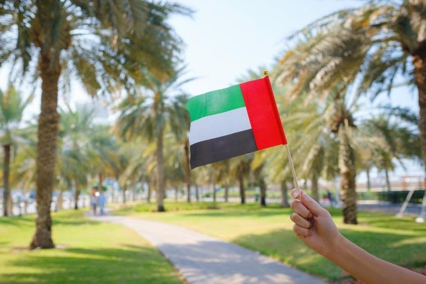 Ruka ženy držiaca miniatúrnu vlajku Spojených arabských emirátov v parku v Abú Zabí.