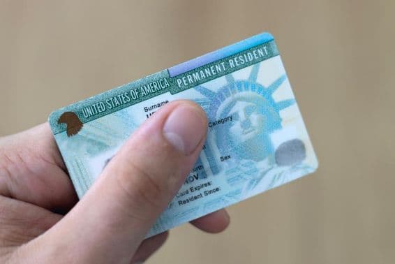 Trvalý rezident v USA drží v ruke zelenú kartu.