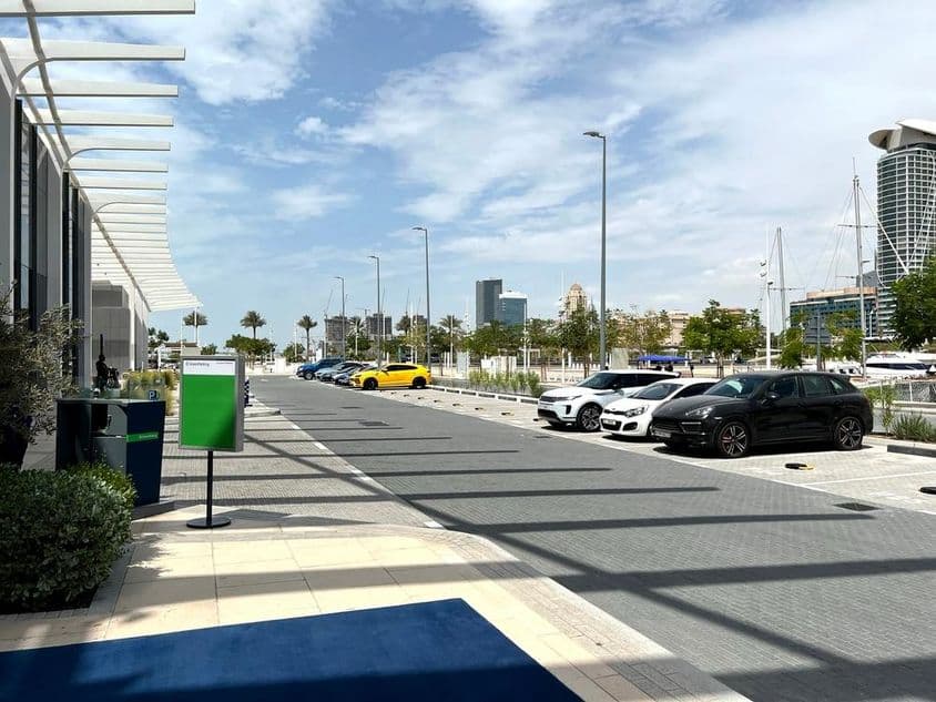 Parkovisko v Dubaji s panorámou mesta v pozadí počas letného dňa.