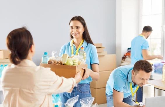 Mladý dobrovoľník rozdáva krabicu s darovaným jedlom tým, ktorí to potrebujú v charitatívnej nadácii.