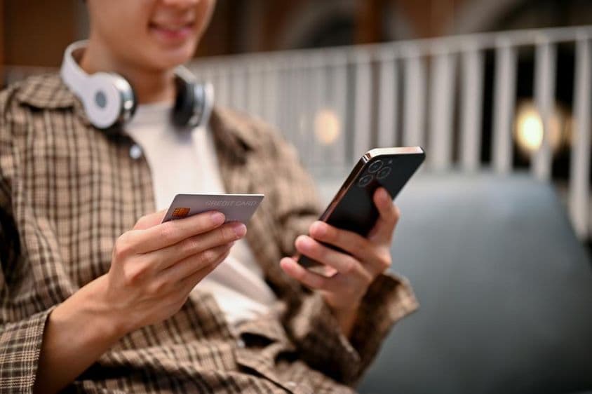 Ázijský muž používajúci službu platby kartou v online nákupnej aplikácii.