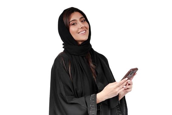 Emirátska podnikateľka v arabskej abaye pracujúca na mobilnom telefóne.