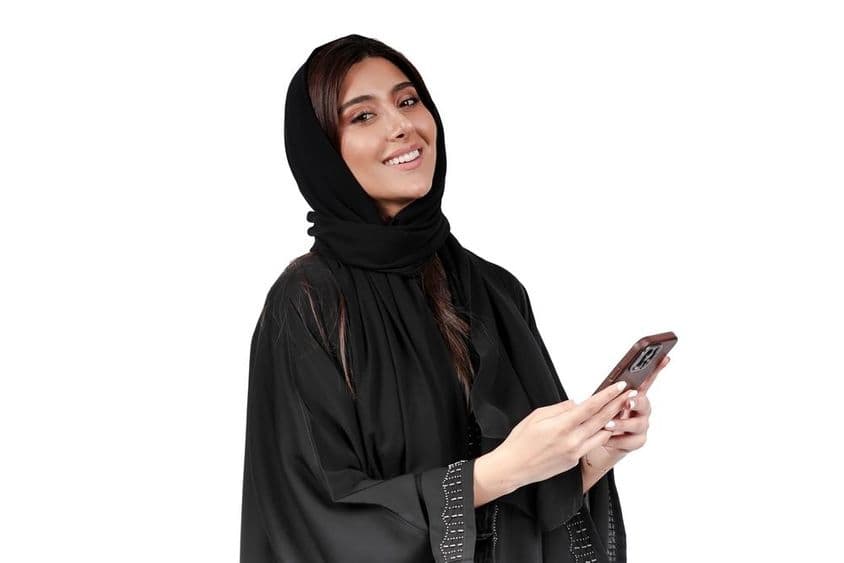 Emirátska podnikateľka v arabskej abaye pracujúca na mobilnom telefóne.