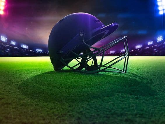 Kriketová prilba zospodu na zelenej tráve.