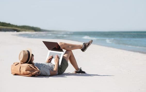 Mladá žena pracujúca na prenosnom počítači pri mori v rámci freelancingu.