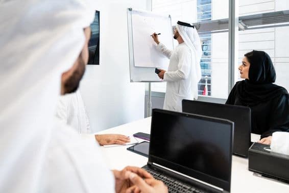 Skupina obchodníkov v tradičnom emirátskom obleku na stretnutí v kancelárii v Dubaji.