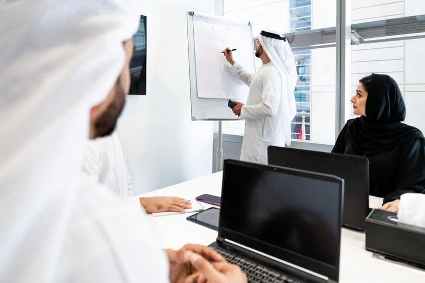 Skupina obchodníkov v tradičnom emirátskom obleku na stretnutí v kancelárii v Dubaji.