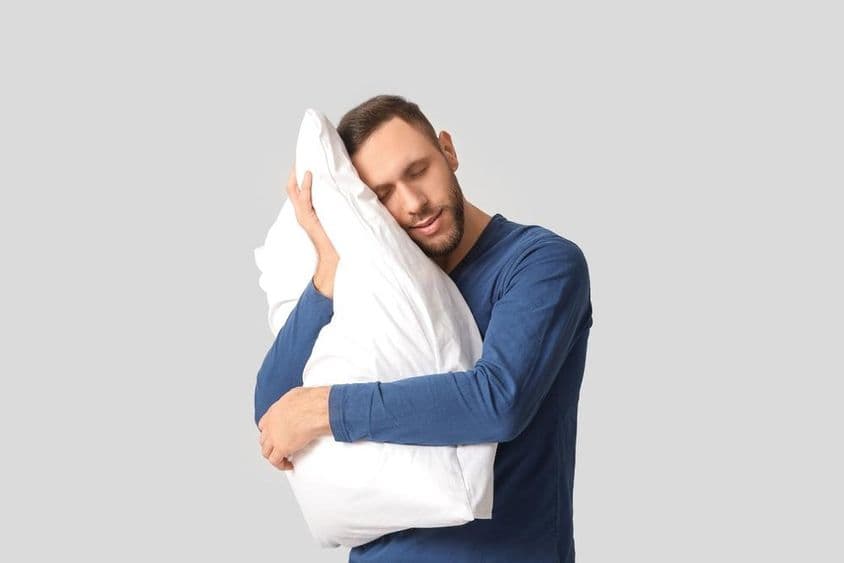 Mladý muž v pyžame s mäkkým vankúšom.