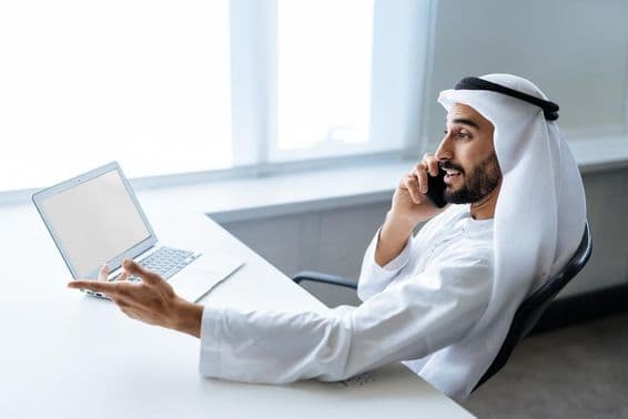 Úspešný podnikateľ v tradičnom emirátskom bielom oblečení pracujúci v Dubaji.