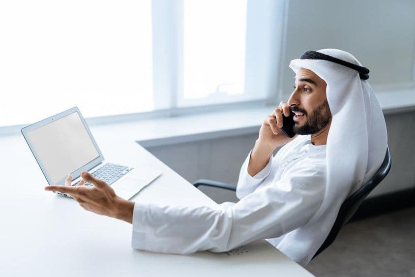 Úspešný podnikateľ v tradičnom emirátskom bielom oblečení pracujúci v Dubaji.