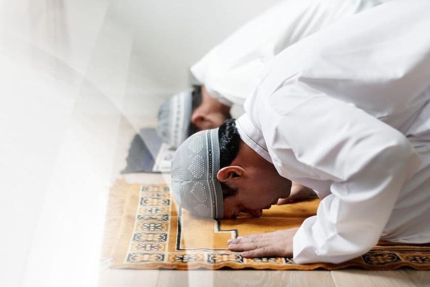 Islamskí muži oblečení v bielom sa ukláňajú v modlitbe.