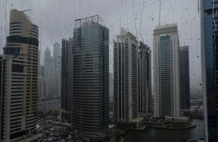 Mokrý okenný pohľad na modernú komerčnú panorámu Dubaja.