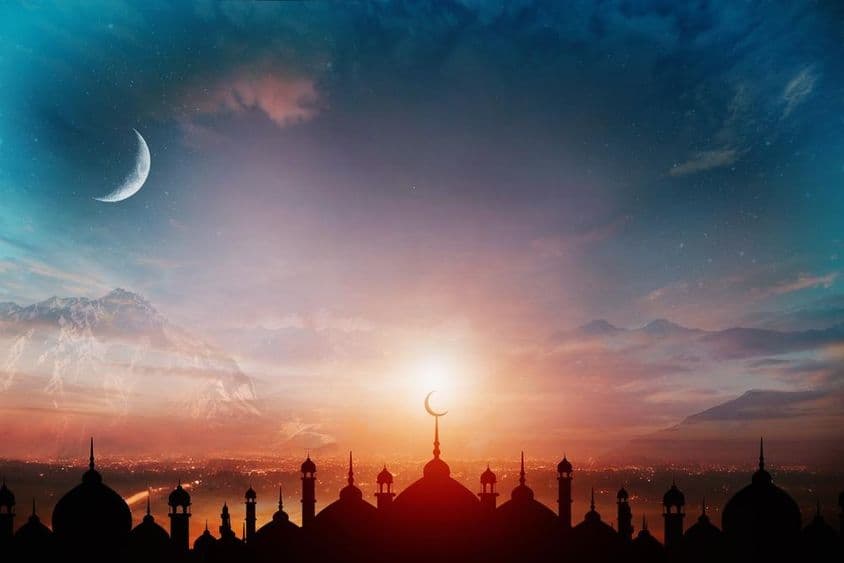 Kopule mešít na pozadí večernej modrej oblohy s polmesiacom.