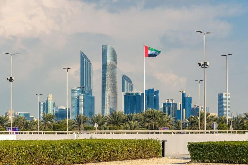 Ikonická panoráma Abu Dhabi s modernými mrakodrapmi a zreteľne viditeľnou národnou vlajkou.