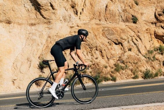 Cyklista v čiernom športovom oblečení sa intenzívne venuje outdoorovému tréningu.