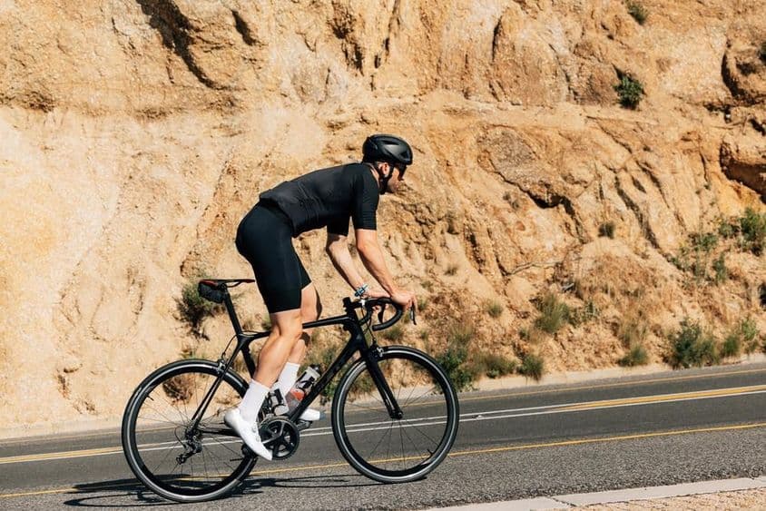 Cyklista v čiernom športovom oblečení sa intenzívne venuje outdoorovému tréningu.