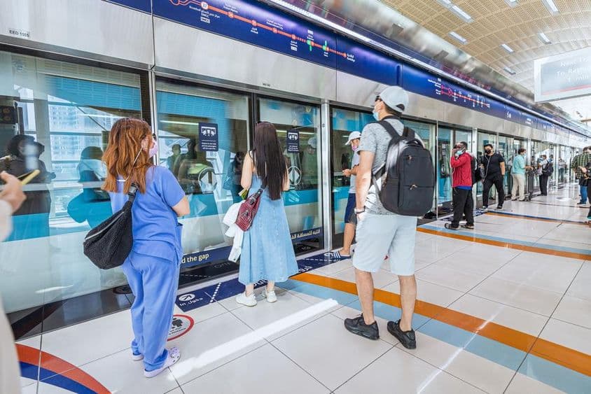Dubaj, cestujúci nastupujúci do prichádzajúceho metra.