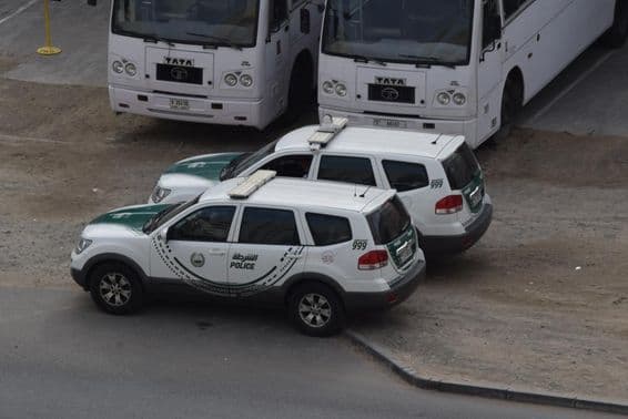 Dve policajné autá v Dubaji zaparkované pred dvoma autobusmi v Al Quoz, Dubaj.
