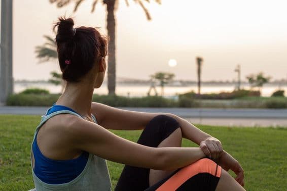 Mladé dievča odpočívajúce po joge v parku na Abu Dhabi Corniche.