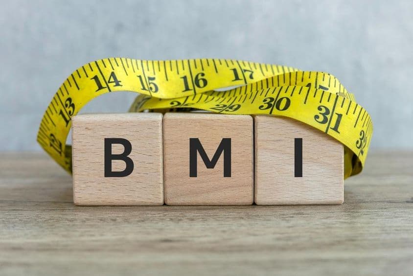 Nápis BMI s drevenými blokmi a meracou páskou.