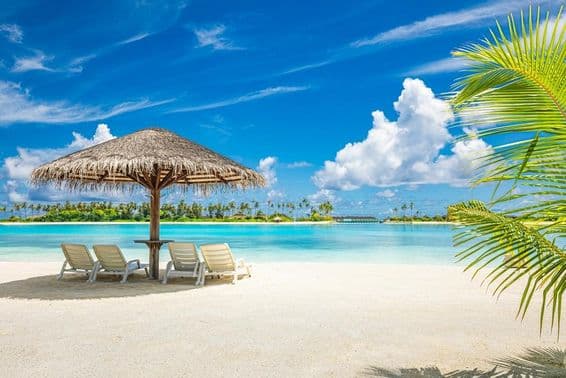 Maldivská piesočnatá pláž s dáždnikom a lehátkom.