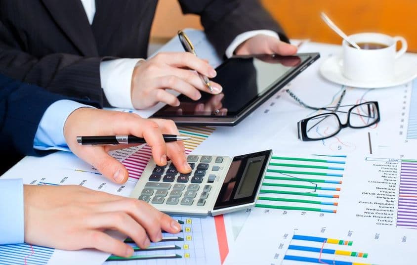 Grafy, kalkulačka, tablet a usilovné ruky študujúce dáta.