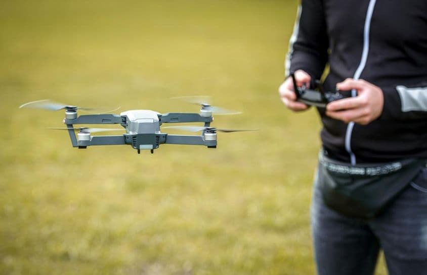 Muž ovládajúci dron pomocou diaľkového ovládača.